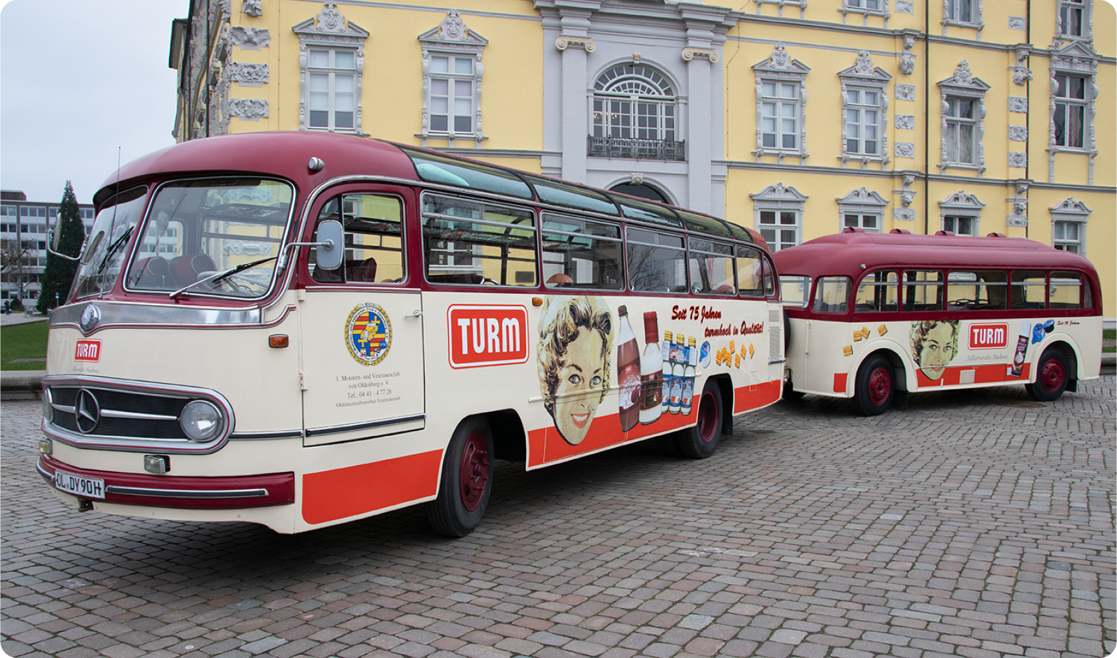 Oldtimerbusse mit nostalgischer TURM Reklame stehen vor geschichtstraechtigem Anwesen